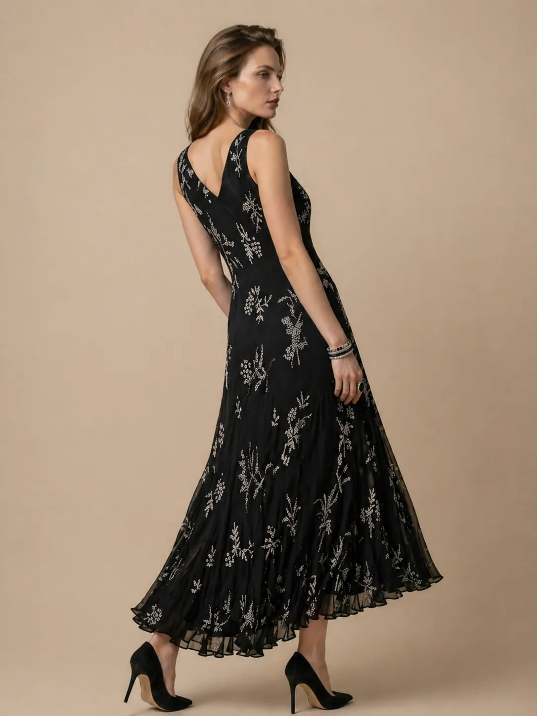 Model in a black floral maxi dress on a beige studio background, back view for e-commerce