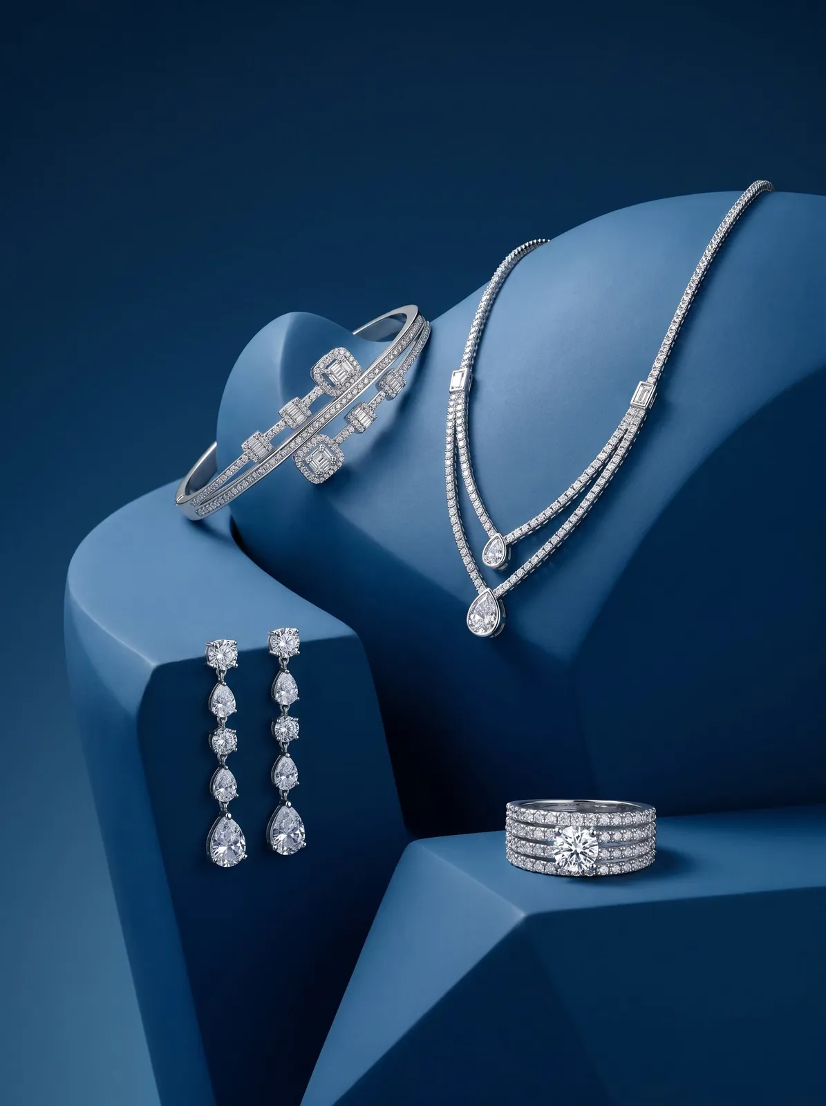 Full diamond jewelry set of earrings, necklace, bangle and ring on blue plinths