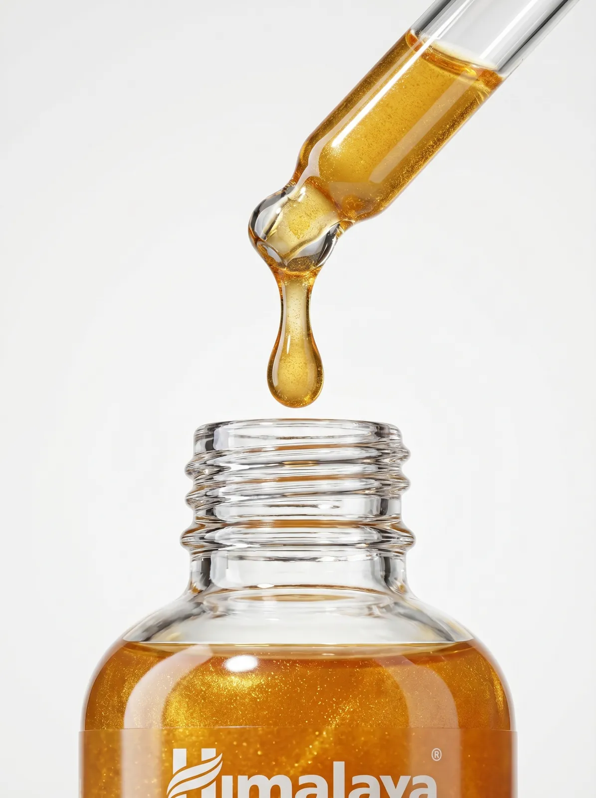 Golden serum dripping from a glass dropper into the bottle, skincare texture close-up